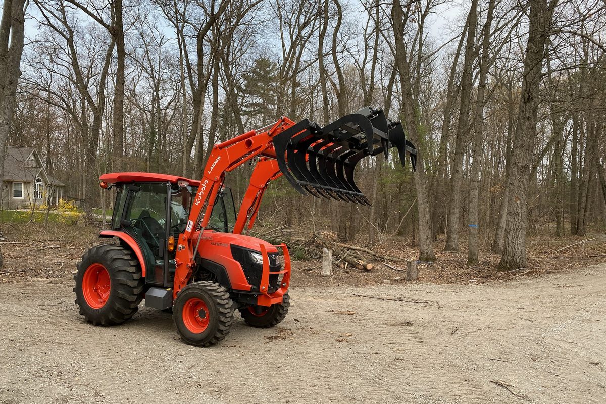 Kubota tractor with root grapple on cleared ground
